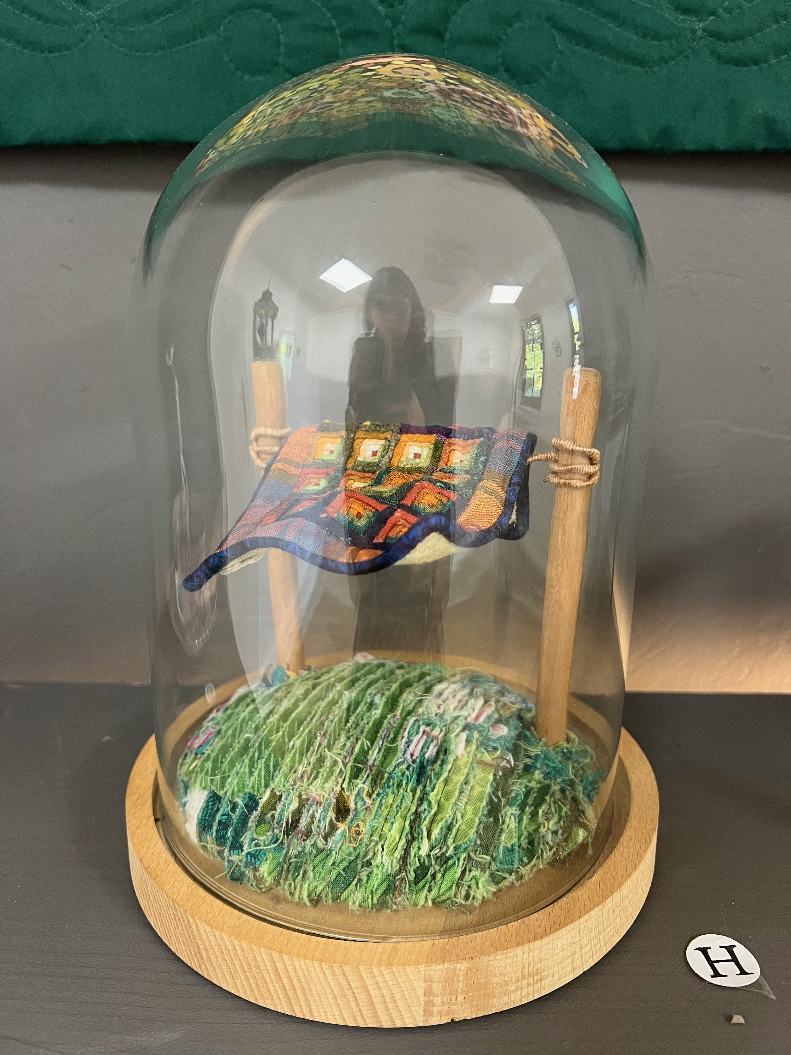 Winziger Logcabin Quilt auf Wäscheleine unter Glaskuppel